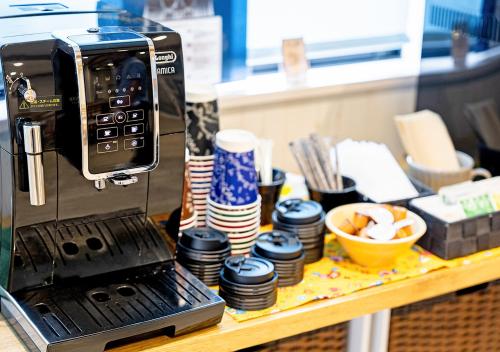 a coffee machine sitting on a table with cups and bowls at Hotel California Miyakojima Resort in Miyako Island