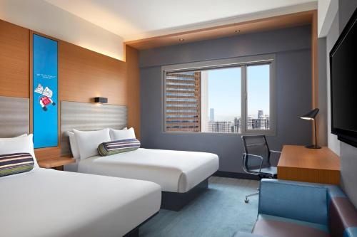 a hotel room with two beds and a desk at Aloft Kuala Lumpur Sentral in Kuala Lumpur