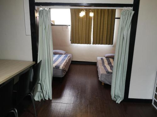 a small room with two beds and a window at Apartment Namba Daikoku in Osaka