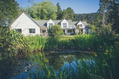 une maison avec un étang en face de celle-ci dans l'établissement Westholm Lodge, à Harihari