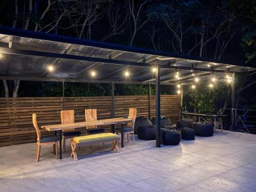 d'une terrasse avec une table en bois, des chaises et des lumières. dans l'établissement Zen Oasis del Bosque, ¡A place to reconnect!, à Calima