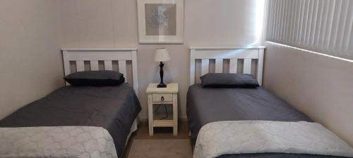 two twin beds in a room with a night stand at Santos 27 Mossel Bay in Mossel Bay