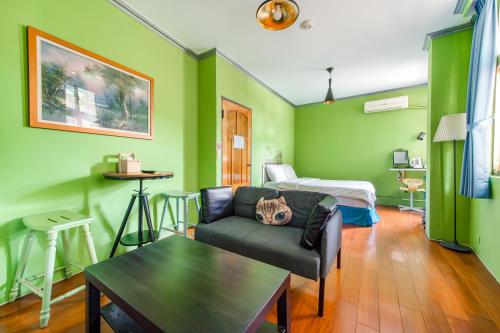 a living room with green walls and a couch and a bed at Ju jiu House in Jiufen