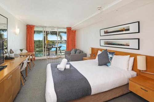 Pelican Waters Golf Resort في كالوندرا: غرفة نوم بسرير ومكتب ومطبخ