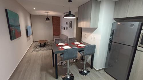 a kitchen with a table with chairs and a refrigerator at Departamento nuevo en Centro Cuauhtémoc in Monterrey