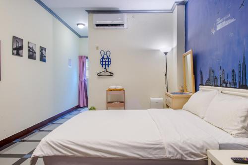 a bedroom with a white bed and a blue wall at Ju jiu House in Jiufen