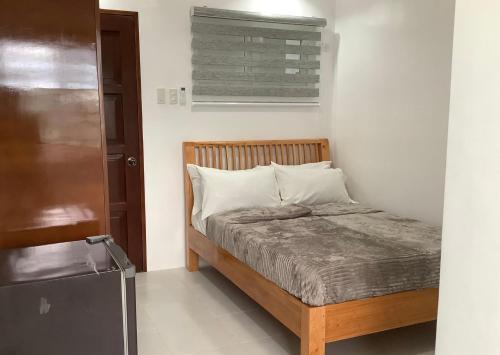 a small bedroom with a bed and a refrigerator at Max n Fe in Iriga City