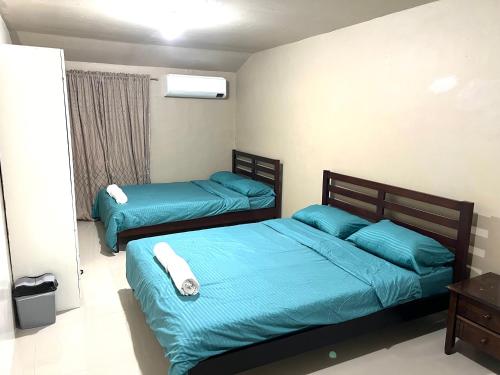 two beds in a room with blue sheets at Aldea Vacation Home in Sibulan
