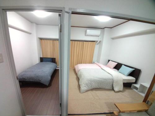 a small room with a bed and a window at Near Tram Apartment Okayama in Okayama