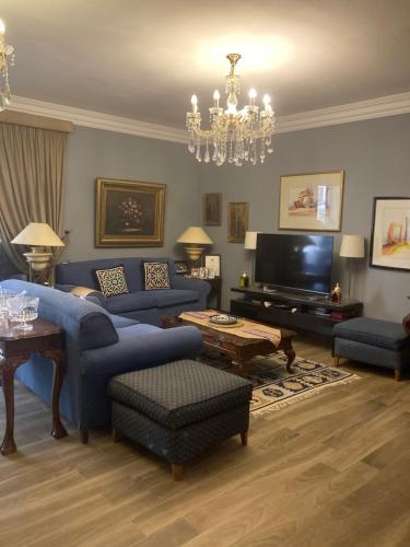 a living room with blue furniture and a chandelier at Grand Egyptian Museum Classic Pyramids Inn in ‘Ezbet `Abd el-Ḥamîd