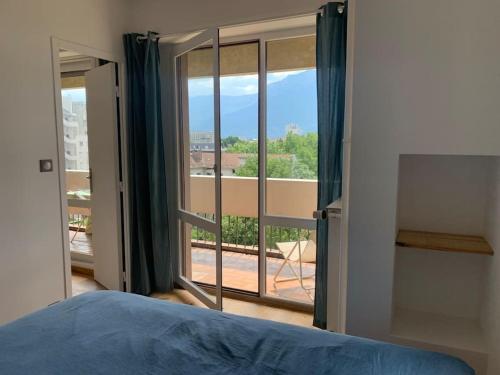 a bedroom with a bed and a view of a balcony at T1 rénové, idéalement situé in Grenoble