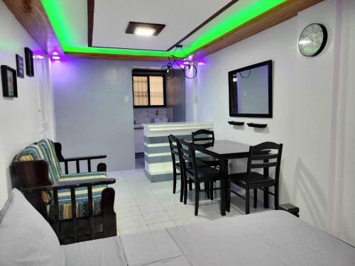 uma sala de jantar com mesa e cadeiras com luzes verdes em Fabuluz Luxury at Princess Place em Malolos