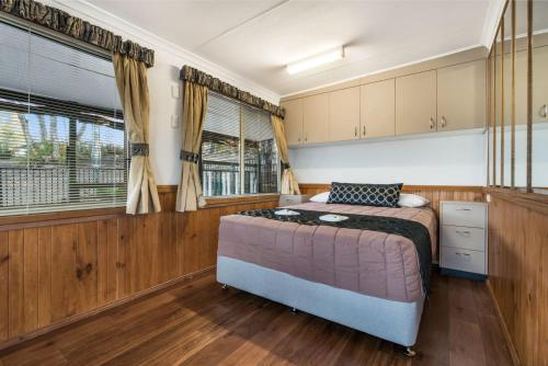 a bedroom with a bed in a room with wooden floors at Reflections Lake Burrendong - Holiday Park in Mumbil