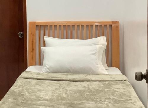 a bed with a wooden headboard and a white pillow at Max n Fe in Iriga City