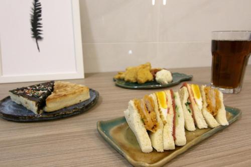 a table with three plates of sandwiches and a glass of beer at 東港日和 in Donggang