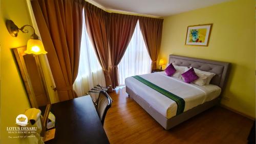 Habitación de hotel con cama con almohadas moradas en Lotus Desaru Beach Resort & Spa en Desaru