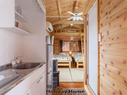 a kitchen with a sink and a room with a bed at もとぶいこいの宿 やまちゃん in Motobu