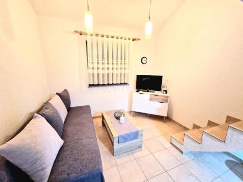 un soggiorno con divano e TV di Apartments Tadic a Omišalj (Castelmuschio)