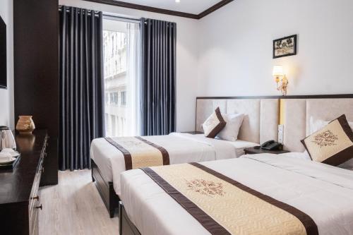 a hotel room with two beds and a window at Navy Hotel Hà Nội in Hanoi