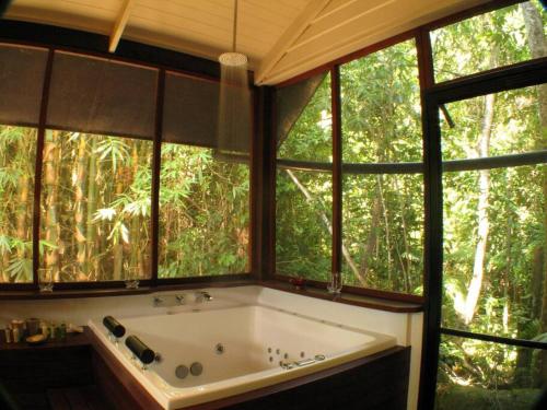 - une baignoire dans une chambre avec fenêtres dans l'établissement Lillypads Yellow Cottage - Rainforest Getaway, à Mission Beach