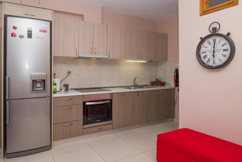 a kitchen with a refrigerator and a clock on the wall at Διαμέρισμα Αριάδνη in Gythio
