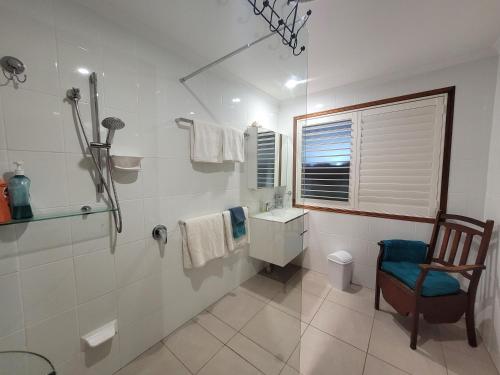a bathroom with a shower and a toilet and a chair at River Heads Appartment in River Heads