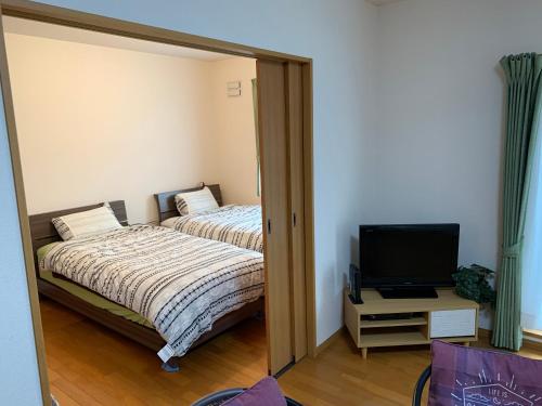 a mirror reflection of a bedroom with two beds and a television at Sejour Toyohirakoen in Sapporo
