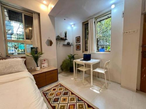 a bedroom with a bed and a table with a laptop on it at Arora Bhavan Studio 1A, Khar West by Connekt Homes in Mumbai