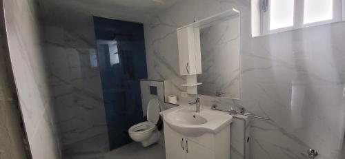 a white bathroom with a sink and a toilet at Jon rooms in Himare