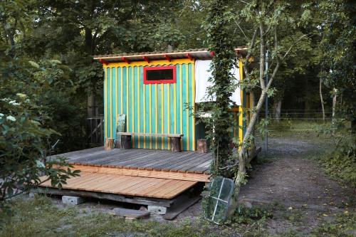 un pequeño cobertizo con un banco en una terraza de madera en Einfachlosmachen-BulliBus, 