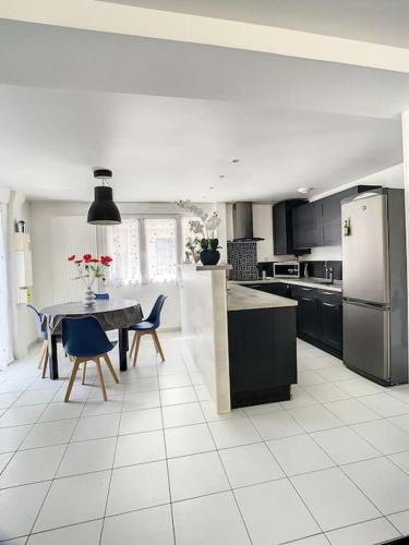 une cuisine avec une table, des chaises et un réfrigérateur dans l'établissement Grande Maison Cosy Terrasse Parking Gare 8 Pers, à Amiens