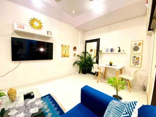 a living room with a blue couch and a tv at Arora Bhavan 1BHK-1B, Khar West by Connekt Homes in Mumbai
