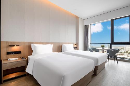 済南市にあるThe COLI Hotel Jinanのベッド2台とデスクが備わるホテルルームです。