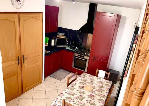 une petite cuisine avec une table et des placards rouges dans l'établissement La belmarienne (à 5 min de Montreuil sur Mer), à Beaumerie-Saint-Martin