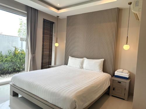 Schlafzimmer mit einem weißen Bett und einem Fenster in der Unterkunft Palm Oasis Pool Villa by Pattaya Holiday in Jomtien Beach