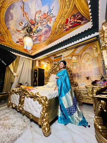 a woman in a blue dress standing next to a bed at Super luxury Gold Room with private pool at Homestay by the tea garden Dibrugarh in Dibrugarh
