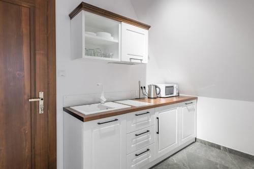a white kitchen with a sink and a microwave at Willa Rzoz in Bukowina Tatrzańska