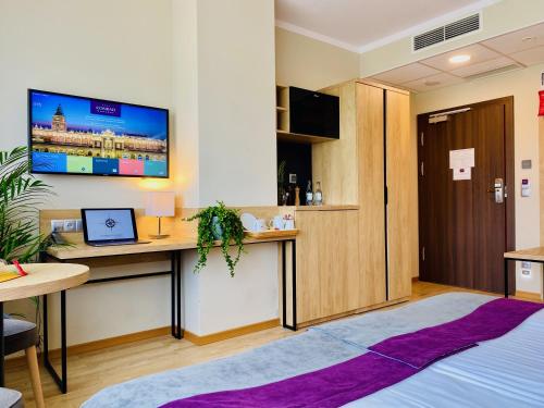 a room with a desk and a tv on the wall at Hotel CONRAD Comfort in Kraków