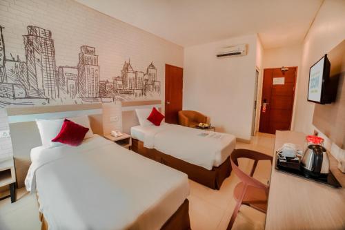 Cette chambre comprend deux lits et un bureau. dans l'établissement Zoom Hotel Mulawarman, à Samarinda