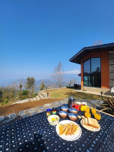 a picnic table with plates of food and drinks at Deumadi Mountain Cottage in Pokhara
