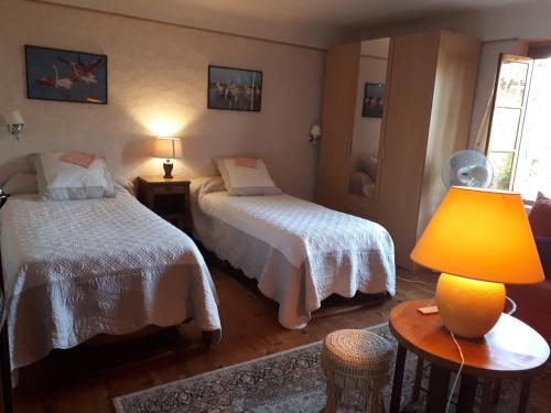 une chambre avec deux lits et une lampe sur une table dans l'établissement presbytere du 12 eme siecle, à Orthoux-Sérignac-et-Quilhan