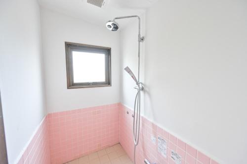 a bathroom with a pink tiled shower with a window at Kagoshima Daiichi Hotel Kamoike in Kagoshima