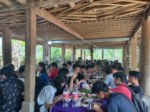 a group of people sitting at tables eating food at Mai Tiến Homestay in Mai Châu