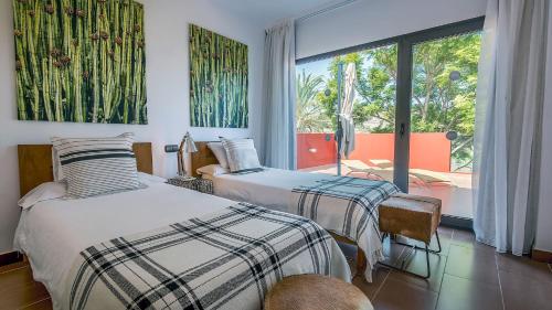 サロブレにあるSalobre Golf Villas Premiumのベッドルーム1室(ベッド2台、大きな窓付)