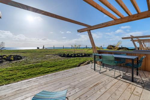 a wooden deck with a table and chairs on the beach at Tasman Holiday Parks - Papamoa Beach in Papamoa