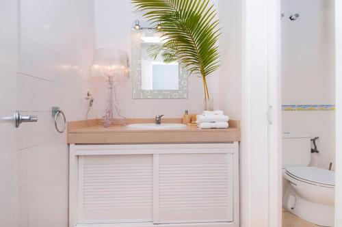 ein Badezimmer mit einem Waschbecken, einem Spiegel und einer Pflanze in der Unterkunft Meloneras Suites in Meloneras