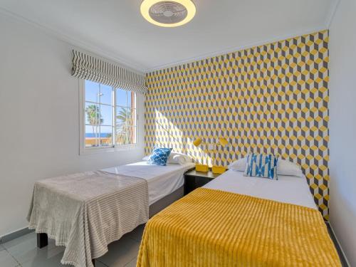 two beds in a room with yellow and blue wallpaper at Timon Suites San Agustin in San Agustin