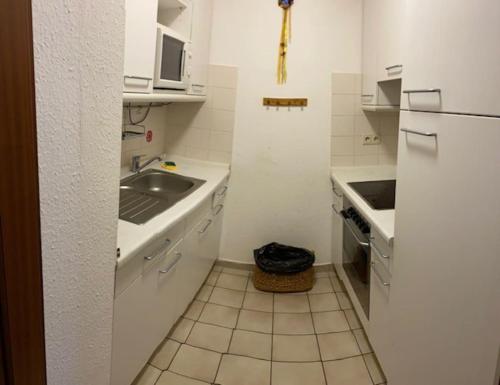 La cuisine blanche est équipée d'un évier et d'un réfrigérateur. dans l'établissement Appartement in Böblingen, à Böblingen