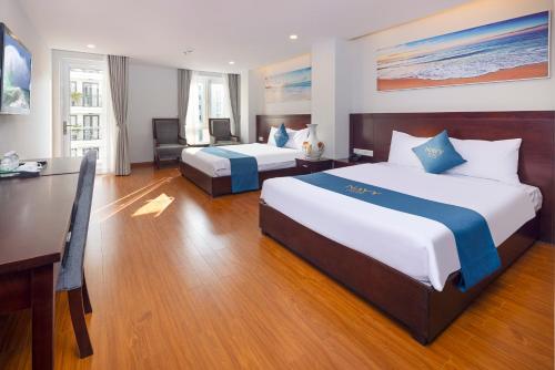 a hotel room with two beds and a desk at Navy Hotel Nha Trang in Nha Trang