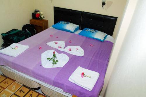 a bed with a purple blanket with towels on it at Yakut Apart Hotel in Dalyan